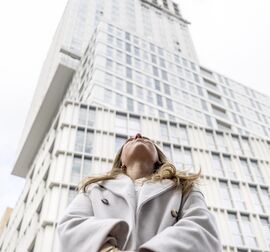 woman looking up in front of high-rise building
